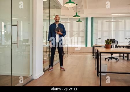 Jeune homme d'affaires souriant avec une tablette dans un bureau Banque D'Images