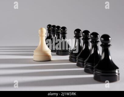 La pièce d'échecs de pion blanc se fait remarquer de la foule des pions noirs. Concept de différence, de diversité ou d'individualité. Banque D'Images