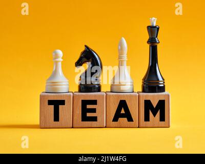 Le mot équipe sur des cubes en bois avec différentes pièces d'échecs. Concept de stratégie de travail d'équipe et de diversité. Banque D'Images