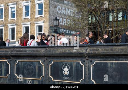 Les gens de l'extérieur et des environs lors d'une journée de printemps ensoleillée traversent le pont routier au-dessus du canal Regents. Camden Town, Londres, Angleterre, Royaume-Uni. Banque D'Images