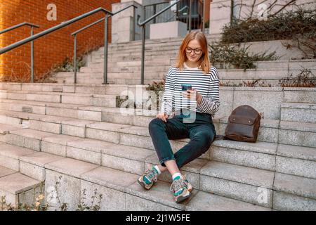 Bonne fille de 20s s'amuser en utilisant le téléphone mobile en plein air dans la ville Banque D'Images