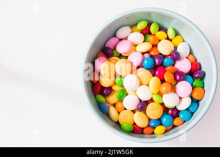 Bonbons colorés dans le bol, bonbons toutes couleurs, fond blanc Banque D'Images