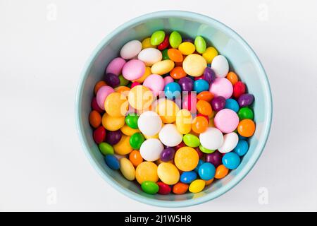 Bonbons colorés dans le bol, bonbons toutes couleurs, fond blanc Banque D'Images