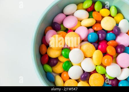 Bonbons colorés dans le bol, bonbons toutes couleurs, fond blanc Banque D'Images