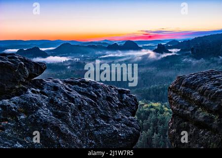 Paysage avec des formations rocheuses dans la région de Zschand du parc national de la Suisse saxonne couvert de brouillard au lever du soleil. Banque D'Images