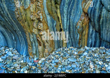 Pile de pierre rugueuse de formes diverses près de la falaise rocheuse avec une surface rugueuse comme arrière-plan texturé Banque D'Images