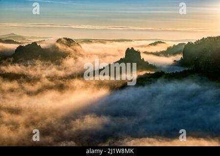 Paysage avec des formations rocheuses et le sommet de Winterstein dans la région de Zschand du Parc national de la Suisse saxonne couvert de brouillard au lever du soleil. Banque D'Images