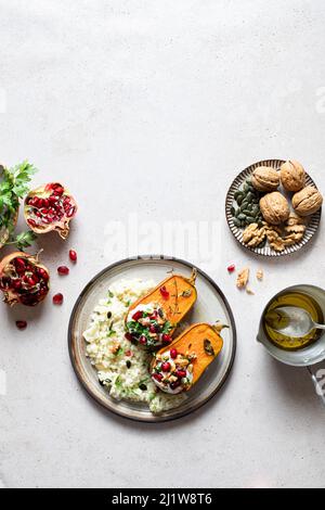Vue de dessus composition de l'assiette avec du riz savoureux et de la citrouille rôtie servi avec des herbes et de la grenade près de l'assiette de noix et d'huile dans le bol Banque D'Images