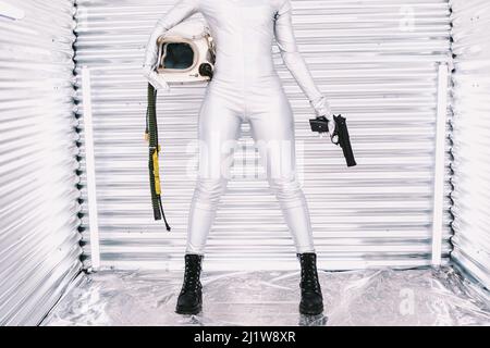Une astronaute afro-américain non reconnaissable a été coupée dans l'espace avec un pistolet à la main, regardant la caméra sur un arrière-plan lumineux Banque D'Images