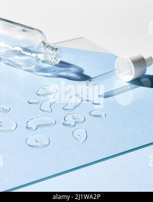 Vider le flacon avec une pipette sur un verre avec des gouttes d'acide hyaluronique pour les soins de la peau sous la lumière du soleil dans la pièce Banque D'Images