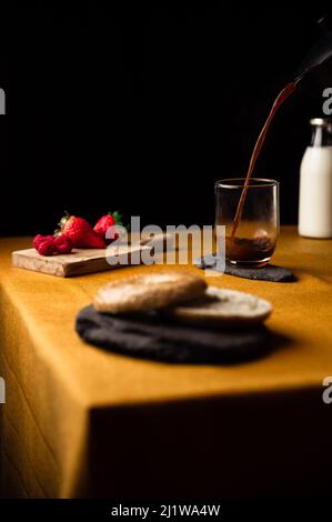 Café frais et parfumé versé dans un verre sur une assiette d'ardoise du pot de moka pour le petit déjeuner avec bagel et framboises avec fraises Banque D'Images