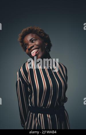 Joueuse afro-américaine avec des cheveux afro porter une tenue à rayures avoir du plaisir en studio et faire un visage drôle Banque D'Images