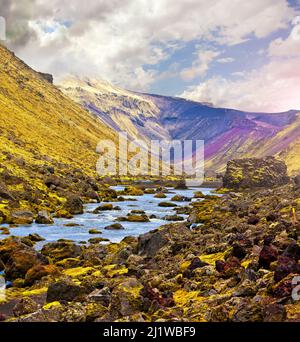 Rivière le long d'une vallée dans Landmannalaugar parmi les paysages montagneux colorés de vert et de magenta, l'Islande Banque D'Images