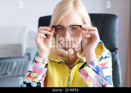 Portrait en gros plan d'une femme d'âge moyen très attirante assise sur sa chaise de bureau et axée sur le travail Banque D'Images