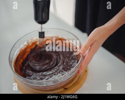 femme mélanger la poudre de cacao, le sucre et la farine pour faire de la pâte avec du chocolat fondu et des noix pour un délicieux gâteau au brownie maison. gâteau fait maison par concept de femme au foyer. Banque D'Images
