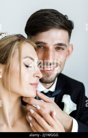 Une jolie mariée habille une mariée dans une robe de mariée. Les jeunes mariés s'embrassent dans la chambre et passent du temps ensemble Banque D'Images