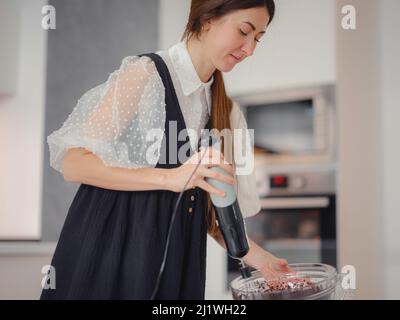femme mélanger la poudre de cacao, le sucre et la farine pour faire de la pâte avec du chocolat fondu et des noix pour un délicieux gâteau au brownie maison. gâteau fait maison par concept de femme au foyer. Banque D'Images