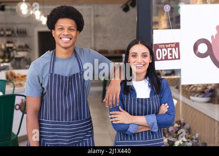 Portrait de jeunes baristas multiraciaux confiants, hommes et femmes, debout à l'entrée du café-restaurant. Non altéré, culture du café, personnes et conc. D'occupation Banque D'Images