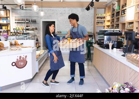 Pleine longueur de jeunes employés multiraciaux heureux qui parlent au café-restaurant. Non modifié, culture du café, gens et concept d'occupation. Banque D'Images