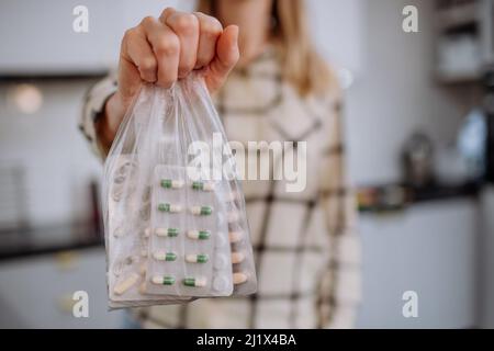 Main de femme tenant les pilules expirées prêtes à recycler. Banque D'Images