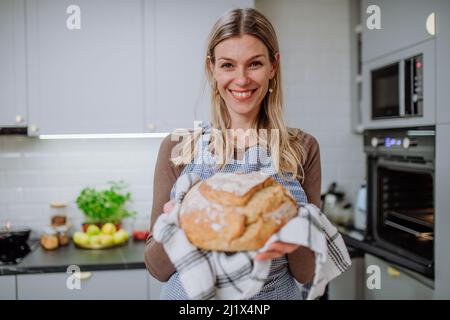 Femme heureuse tenant du pain de levain maison, la cuisine à la maison concept. Banque D'Images