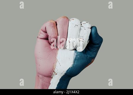 gros plan du poing relevé d'une personne avec le drapeau de fierté transgenre peint en lui, sur un fond blanc cassé Banque D'Images