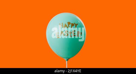 un ballon bleu avec le texte happy easter écrit, sur fond orange Banque D'Images