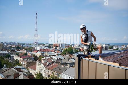 Les ouvriers de l'alpinisme industriel lavent les fenêtres en verre d'un bâtiment de grande hauteur. Alpiniste travaillant avec des cordes d'escalade sur le toit du gratte-ciel. Banque D'Images