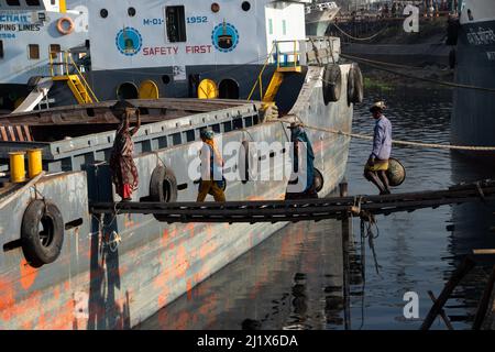 13 mars 2022, Dhaka, Dhaka, Bangladesh : les travailleurs transportent des paniers pleins de charbon sur leur tête, alors qu'ils déchargent le charbon d'un cargo à Dhaka. Environ 3,0 % de l'énergie du pays provient actuellement du charbon. En début de matinée, les travailleurs commencent à décharger les charbons jusqu'au coucher du soleil, ils gagnent $5 à $7 USD par jour. Il n'y a pas de chaussures spéciales sur leurs pieds et pas de gants dans leurs mains pour décharger le charbon des navires de cargaison. En outre, de longues heures de travail sous le soleil brûlant, une accumulation massive de poussière et le transport de charges excessives posent de graves risques pour la santé des travailleurs. (Image crédit : © Banque D'Images