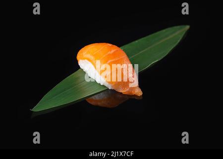 Manger des sushis. Délicieuse cuisine japonaise. Délicieux sushis nigiri frais traditionnels avec saumon sur fond noir et reflet. Menu sushi. JAPA Banque D'Images