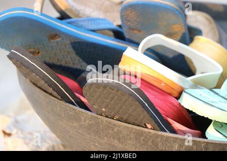 Ensemble de chaussures utilisées placées dans un panier, flifflop coloré dans un panier Banque D'Images
