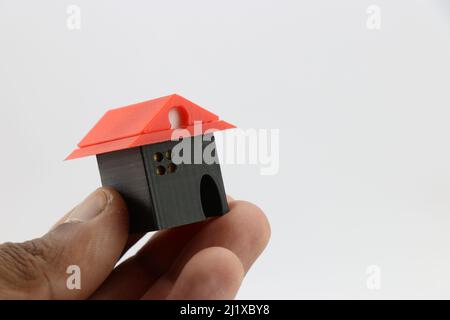 La petite maison modèle tenue à la main sur fond blanc, maison miniature faite de 3D pièces imprimées Banque D'Images