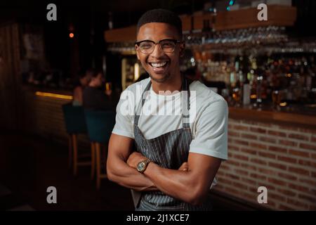 Portrait d'un serveur masculin en train de rire au travail avec un tablier Banque D'Images