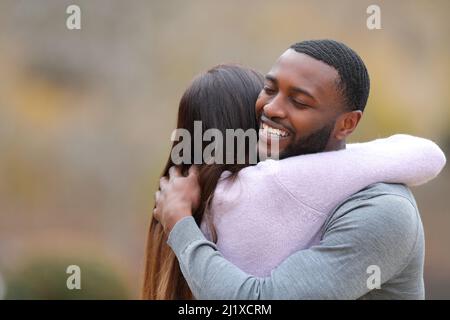 Couple qui s'embrasse à l'extérieur et homme heureux souriant dans un parc Banque D'Images