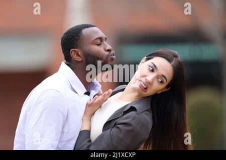 Homme à peau noire essayant de s'embrasser à une femme caucasienne qui le tire dans la rue Banque D'Images
