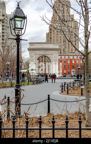 Washington Square Arch, New York City pendant l'hiver avec peu de personnes marchant dans le parc, couvert, feu de rue en avant, vue de loin, verti Banque D'Images