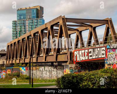 Pont de chemin de fer avec graffiti vu de Station Park dans le quartier de Spitalfields de Londres, avec un bâtiment moderne de haute élévation dans le loin. Banque D'Images