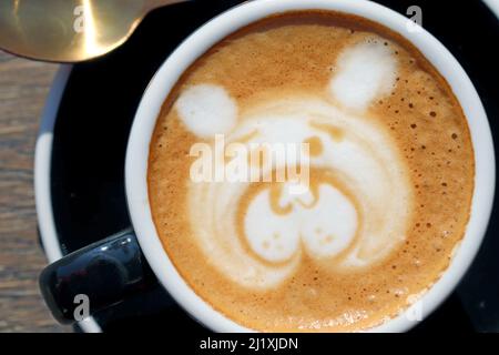 Latte art, dessin du visage de l'ours, café art réalisé par le barista sur une table en bois, vue du dessus ou du dessus. Gros plan. Banque D'Images