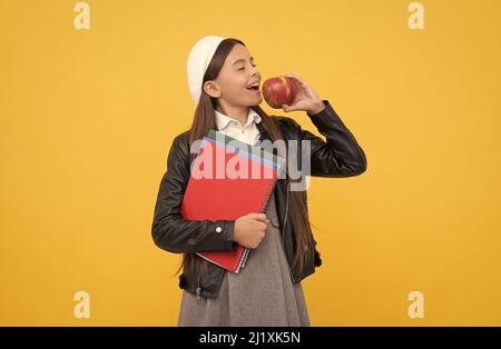 Heureux enfant d'âge scolaire profiter de manger savoureux bio vitamine pomme jaune fond, nourriture saine Banque D'Images