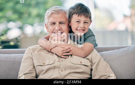 Il met le grand en grand-père. Portrait d'un adorable petit garçon reposant avec son grand-père sur le canapé à la maison. Banque D'Images