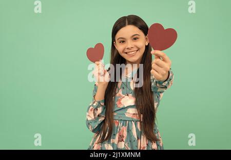 un enfant souriant tient le cœur rouge symbole de l'amour pour la saint valentin, l'amour Banque D'Images