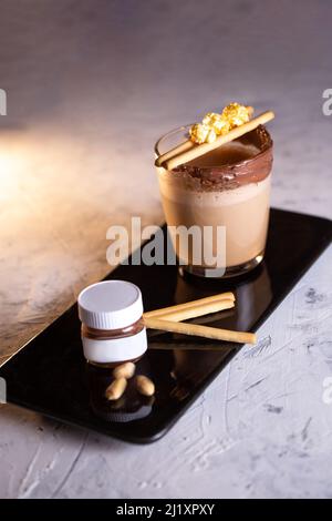 Café avec biscuits et pâte de chocolat sur une assiette noire Banque D'Images