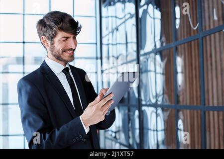 homme d'affaires souriant utilisant une tablette numérique au bureau. Banque D'Images