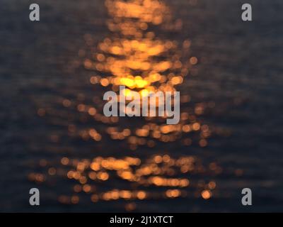 Vue rapprochée du coucher de soleil se reflétant dans la surface d'eau floue de l'océan Atlantique sur la côte sud de la Grande Canarie, îles Canaries. Banque D'Images