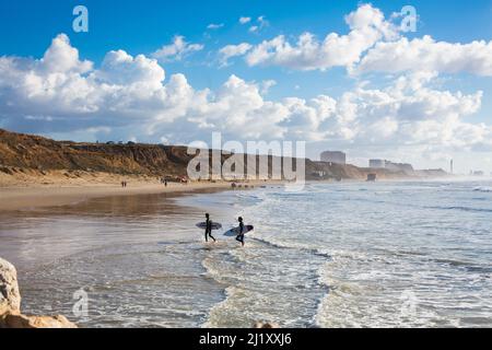 Deux surfeurs marchent le long de la mer. Banque D'Images