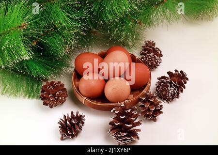 Studio photo des oeufs de Pâques dans un panier avec plusieurs Pinecones et l'épinette verte sur fond blanc Banque D'Images