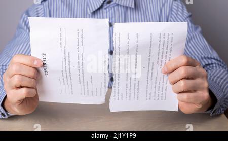 Homme mains rupture de contrat. Résiliation de l'accord, de la transaction ou du concept de licenciement d'un employé. Homme assis à un bureau et tenant des pièces déchirées de documents. Photo de haute qualité Banque D'Images
