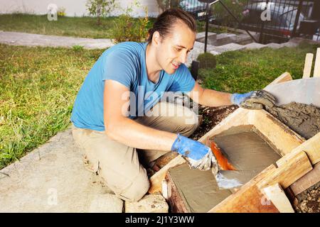 Homme travaille avec la truelle faisant un escalier en béton au jardin de la maison Banque D'Images