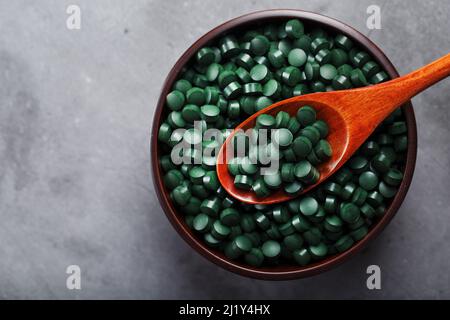 Vitamines de spiruline dans une tasse en bois avec une cuillère en bois sur fond sombre Banque D'Images