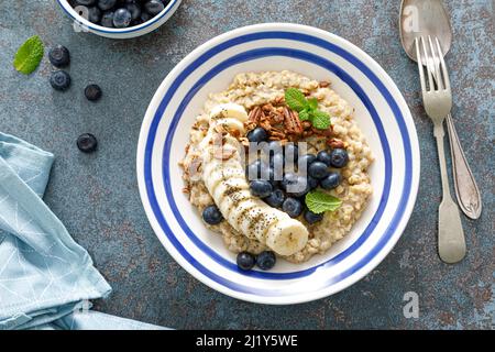 Flocons d'avoine avec des bleuets et des pacanes frais et de la banane Banque D'Images